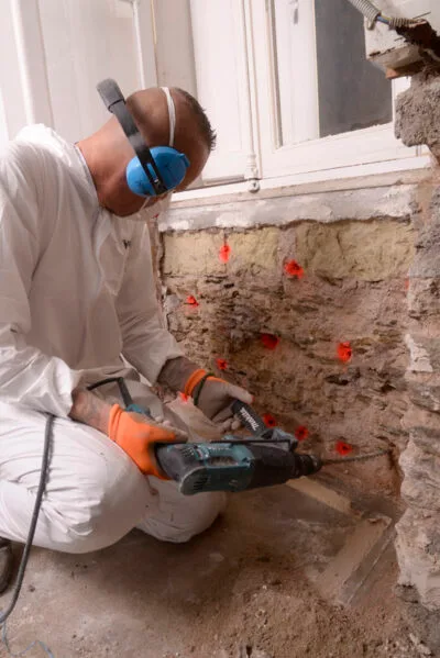 Perçage de mur en pierre avant traitement de la mérule par un professionnel dans le Maine et Loire